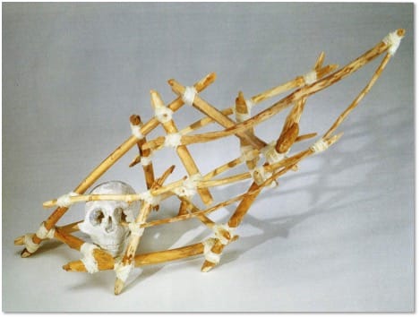 A long horizontal lattice of pale sticks lashed at the joints, enclosing a small skull at its left end.